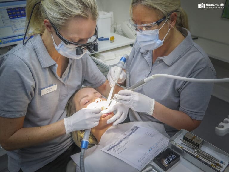 Mennesker – Tandlæge udfører behandling af patient i tandlægestol med mundspejl og bor.